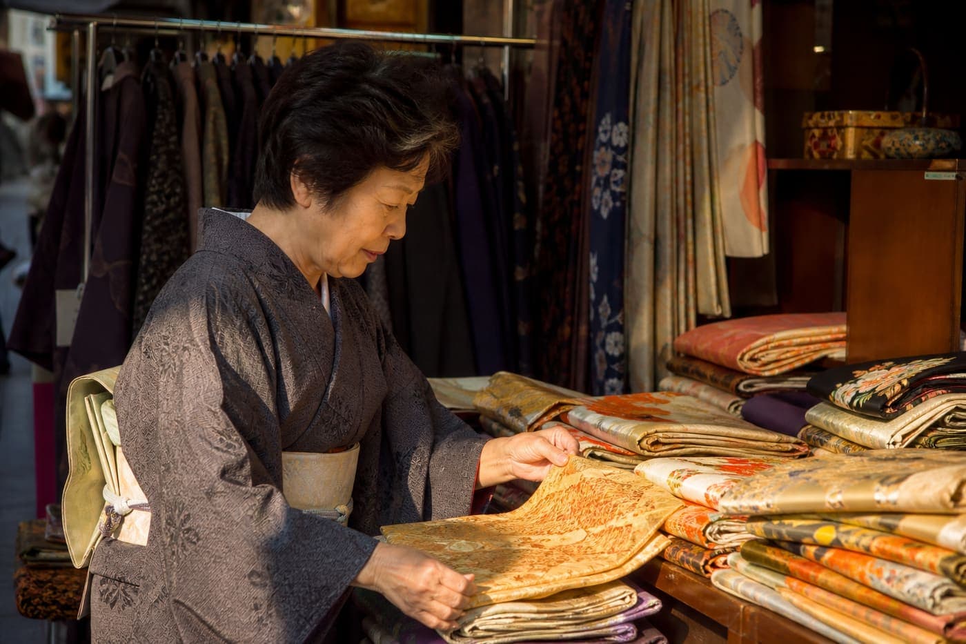 Kyoto vendor arranging vintage obi at a market stall